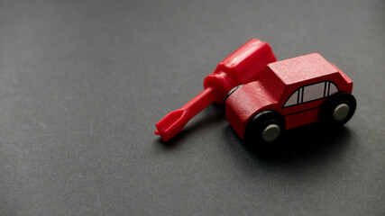 Car maintenance, car service or car repair concept. A toy car and screwdriver on a black background with copy space.