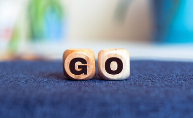Go - text made of wooden cube on blur background.