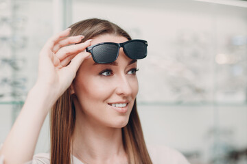 Young Woman with Black punched eyeglasses for vision training. perforated glasses trainer.