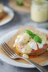 Egg benedict sandwiches - muffin with poached egg, ham and hollandaise sauce