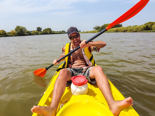 A young man in the canoe doing canoeing in the a natural park of Catalonia, river next to the beach...
