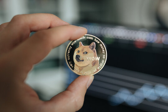 Dogecoin meme coin. Cryptocurrency closeup held between two fingers