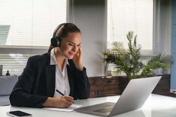 Businesswoman is sitting and listening to podcast via headphones