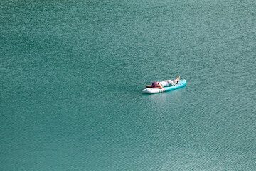 The girl is sunbathing on a sapa on a pond with turquoise water