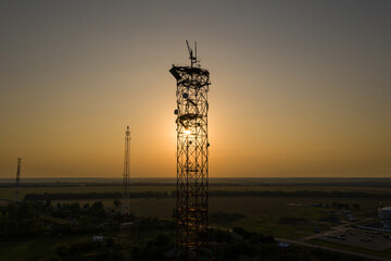 The sun shines through the silhouette of telecommunication towers