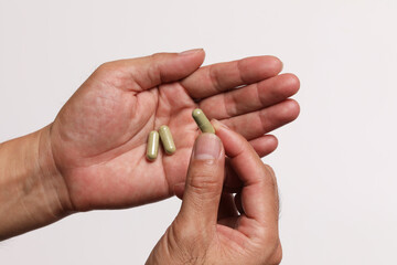 Close up of hands with Andrographis paniculata capsule.