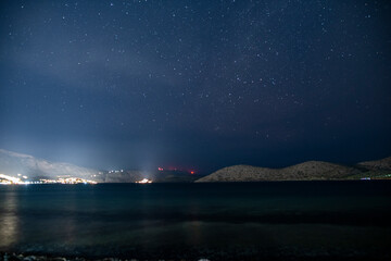 starry sky over mountains, sea and ancient buildings on the island of Crete