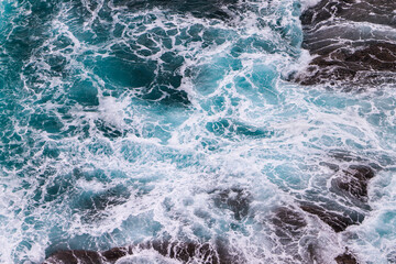 Arial view of whirling, swirling, rough turquoise water at the bottom of a cliff. No people, copy space. Background.
