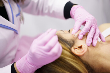 Doctor injecting PDO suture treatment threads into the face of a woman.