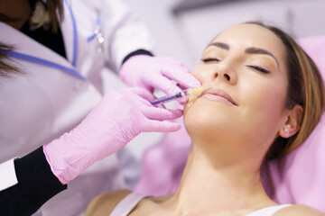 Doctor injecting hyaluronic acid in the face of a woman as a facial rejuvenation treatment.