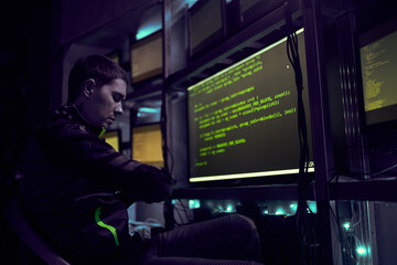 Hacker is working with computer typing text in dark room.
