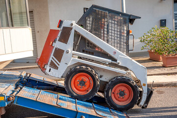 mini excavator transported on the truck, by means of ramps it is unloaded by an operator