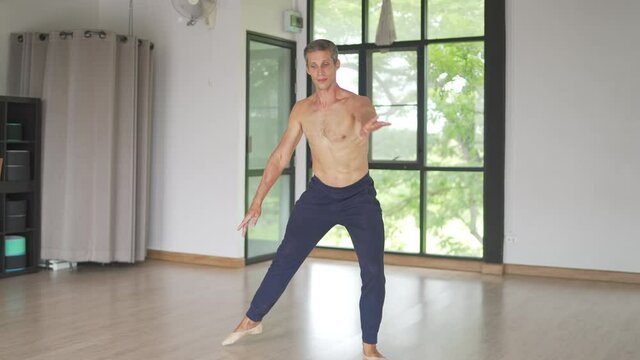 4K Confidence Caucasian male ballet dancer practicing ballet dance alone in studio room. Handsome man athletic dancing classic ballet showing performance body stretching and strength muscle.