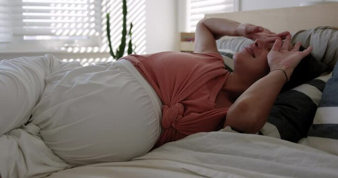 Pregnant mother waking up from afternoon day nap in bed - relax and rested