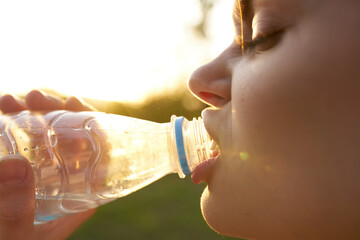 cheerful woman drinking water from a bottle and close-up nature summer