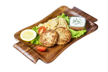 Fish cutlets with garnish on a vintage wooden plate, isolated on white. Top view.