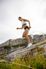 Side view of fitness woman doing high-intensity running on mountainside