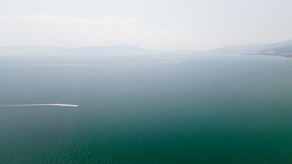 Panoramic drone clip of a small tropical peninsula with a boat passing by in Strimonas, Macedonia, North Greece