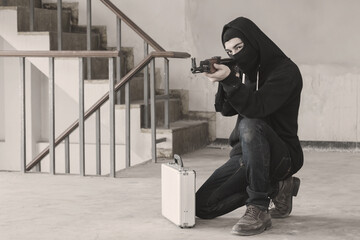 Terrorist hold a pistol gun aiming eye contact with blurred background.