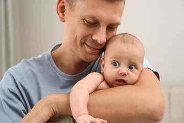 Happy father holding his cute baby at home, closeup