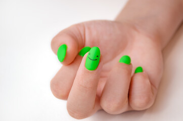 A woman's hand with a manicure and green gel polish. Well-groomed nails. The middle finger points up, a rude gesture.