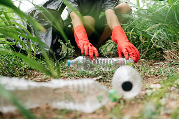 Fototapeta premium Boy man hand pick up plastic bottle in the forest. nature conservation and Environment concept.
