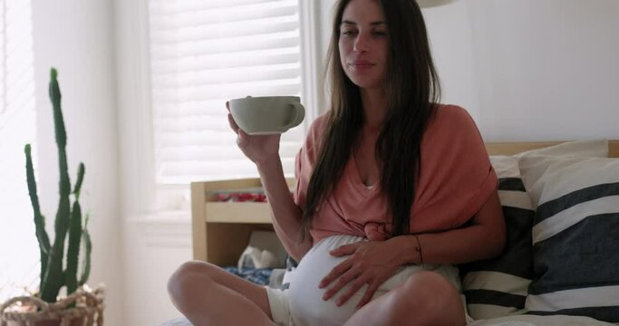 Pregnant woman has braxton hicks contraction then talks to her baby - wide shot