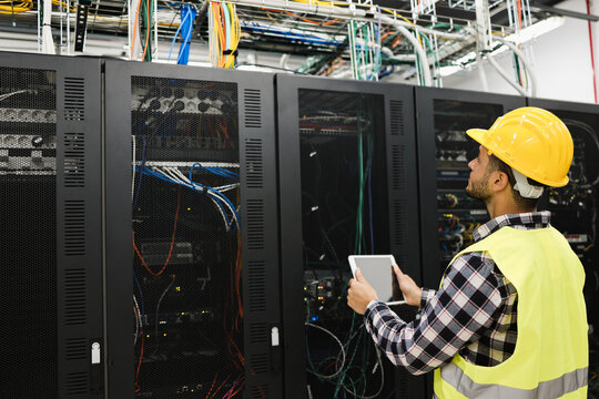 Young technician man working with tablet inside big data center room - Soft focus on face