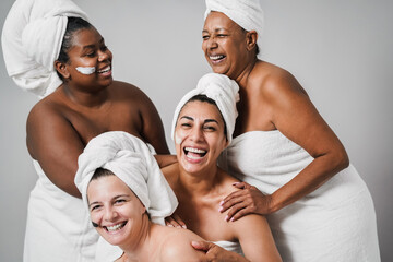 Multigeneration women with diverse skin and body laughing together while wearing body towels -...