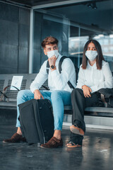 Trabajadores de negocios con mascarilla en espera con sus equipajes y mochilas el transporte público 