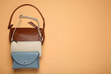 Different stylish women's bags on pale orange background, flat lay. Space for text