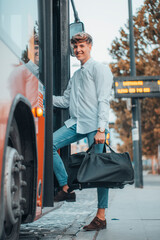 Hombre de negocios sonriente y entusiasmado subiendo al autobús con su equipaje de mano © Migue Suarez