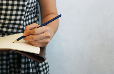 Female left hand uses a pencil write on a book.