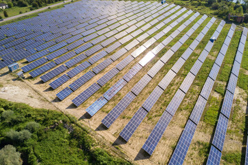 Aerial view of solar power plant on green field. Electric farm with panels for producing clean ecologic energy.