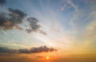 Bright colorful sunset sky with setting sun and vibrant clouds.