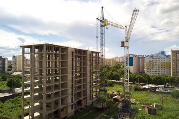 Aerial view of high tower crane and residential apartment buildings under construction. Real estate development.