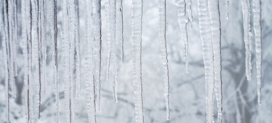 Icicles hanging on the roof. Winter nature abstract art. Physical phenomenon, solid form of water.
