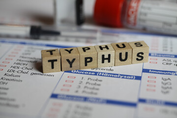 Viersen, Germany - June 1. 2021: Closeup of word typhus on laboratory requisition slip with syringe and vial