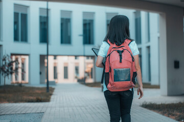 Muchacha joven paseando por el campus de la universidad con mochila para entrar al aula