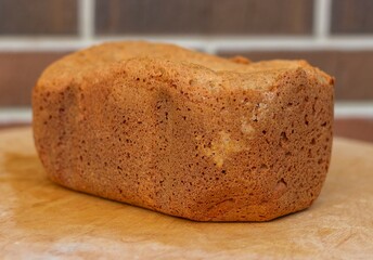 Appetizing ruddy bread on a wooden tray against a background of brown brickwork