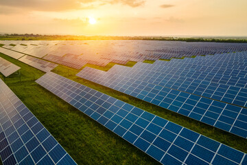 Aerial view of large sustainable electrical power plant with many rows of solar photovoltaic panels for producing clean ecological electric energy in morning. © bilanol