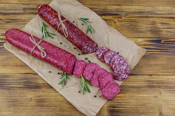 Salami sausages on craft paper on a wooden table. Top view