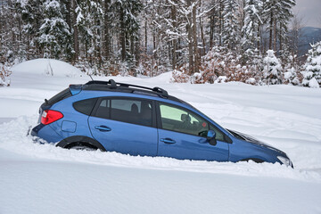 Car stuck in deep snow on cold winter day.