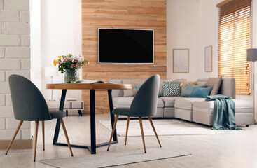 Modern wide screen TV on wall in room with stylish furniture