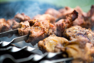 Shashlik or shish kebab preparing on barbecue grill over hot charcoal. Grilled pieces of pork meat on metal skewers.