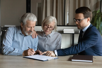Mature couple signing contract, making insurance investment deal with manager broker or realtor in office, businessman in glasses consulting senior family, pointing finger at document agreement