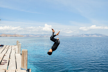 A man does a backflip into the water