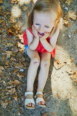 Cute little girl sitting on the ground after falling down