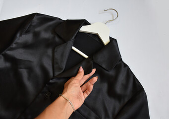 a woman's hand touches a man's silk black shirt