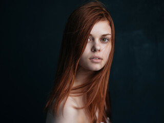 Fototapeta premium woman with bare shoulders and red hair makeup dark background
